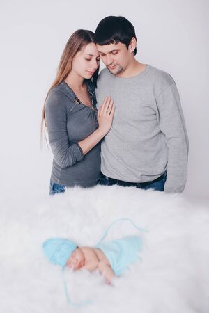 the concept of parenthood, children's Day, medicine, IVF-father and mother looks at the sleeping newborn and stroking it. Isolated on white background.の写真素材
