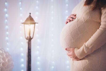The concept of health, ECO - pregnant woman's stomach close-up. Girl stroking. Decorative lantern as backgroundの写真素材