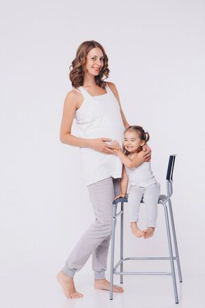 Happy kid girl hugging pregnant mother's belly, pregnancy and new life conceptの写真素材