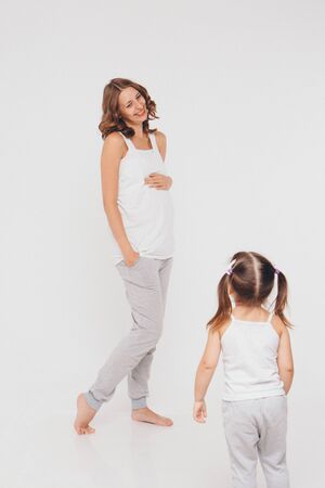 mom and daughter having fun on a white background. Pregnant woman and child play together. concept of childhood, healthcare, IVFの写真素材