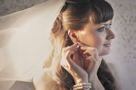 the bride tries on jewelry. The model shows an earring. French manicure with rhinestonesの写真素材