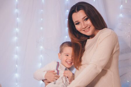 the child in the arms of his mother on the background of lights and decorative elementsの写真素材