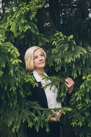 the concept of working on the street, day rest - a Fashionable stylish portrait of a woman with white short hair. businesswoman walking in the Park among the trees.の写真素材