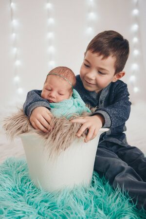 the concept of a healthy lifestyle, the protection of children, shopping - a teenager with a newborn baby playing together. Happy kids: brother and sister on white backgroundの写真素材