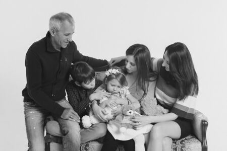 concept of happy childhood, family, love - group of people on a white background: adults and children with toys sitting on the same couchの写真素材