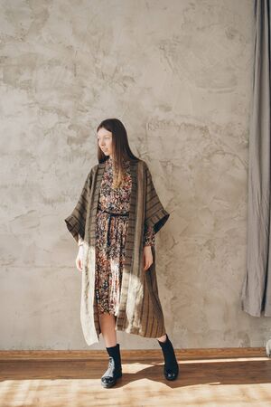 beautiful caucasian woman in Japanese kimono and black shoes on the background of the home interior. Model advertising clothesの写真素材