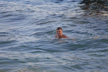 tanned man on vacation swimming in the poolの写真素材