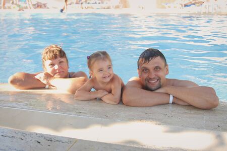 a group of men swimming in the pool. man woman and child on a vacation. Concept of recreationの写真素材