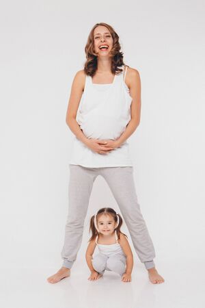 mom and daughter having fun on a white background. Pregnant woman and child play together. concept of childhood, healthcare, IVFの写真素材