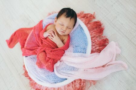 newborn baby wrapped in a blanket sleeping in a basket. concept of childhood, healthcare, IVFの写真素材