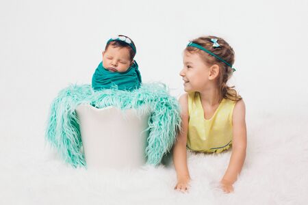 the concept of a healthy lifestyle, the protection of children, shopping - a teenager with a newborn baby playing together. Happy kids: brother and sister on white backgroundの写真素材