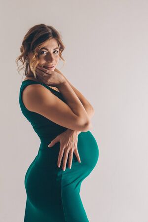 the pregnant woman in green dress thought on white background. The concept of healthy digestion, lifestyle, IVFの写真素材