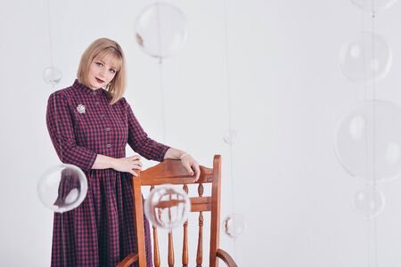 work concept, model business - fashionable stylish portrait of a woman with white short hair. model in purple dress with brooch sitting on chair on white backgroundの写真素材