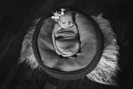 newborn baby with a flower on his head, wrapped in a blanket, sleeping in a basket. the concept of childhood, health, IVFの写真素材
