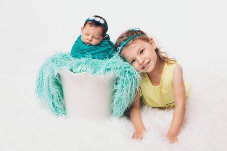 the concept of a healthy lifestyle, the protection of children, shopping - a teenager with a newborn baby playing together. Happy kids: brother and sister on white backgroundの写真素材