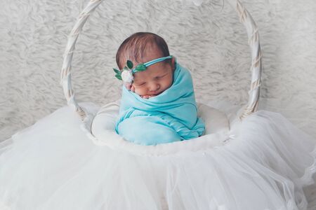 newborn baby with a flower on his head, wrapped in a blanket, sleeping in a basket. the concept of childhood, health, IVFの写真素材
