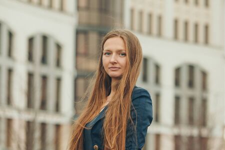 portrait of a beautiful girl with red haired on the background of the urban landscape