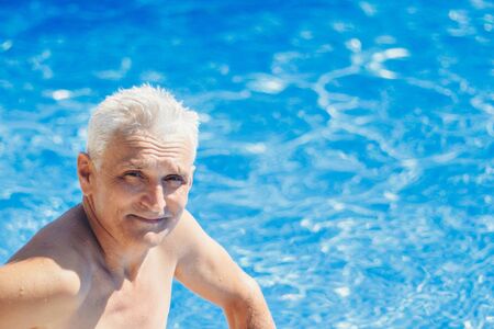 portrait of an adult man with gray hair near the water. The concept of tanning, recreation, tourismの写真素材