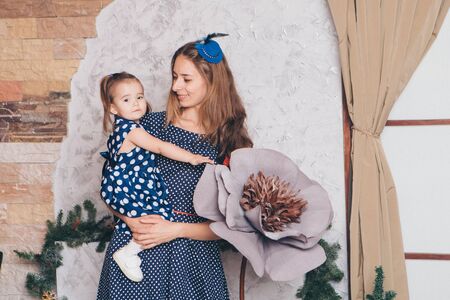 the child in the arms of his mother. A woman with a child in her arms next to a large flowerの写真素材