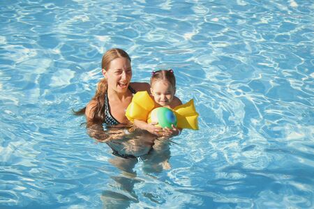mother and daughter in armrests for swimming on vacation in the pool. The concept of Spa, swimming lessons, vacations, water treatmentの写真素材