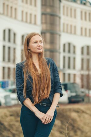 portrait of a beautiful girl with red haired on the background of the urban landscapeの写真素材