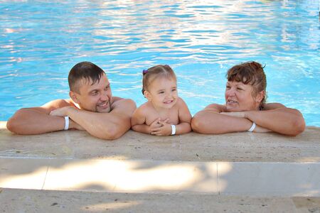 a group of men swimming in the pool. man woman and child on a vacation. Concept of recreationの写真素材