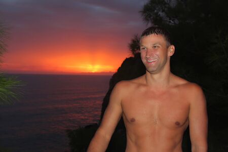 the concept of tourism, recreation-a happy man overlooking the sea and the sunsetの写真素材