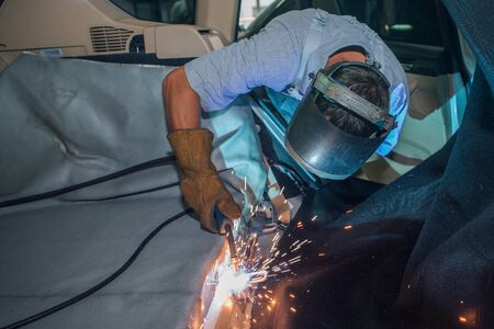repair of the car interior. the man works with the welding in the trunk
