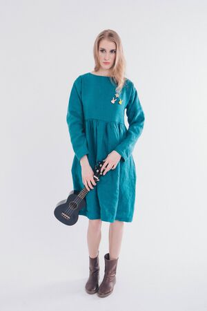 beautiful girl in blue dress with small guitar in hands on white background. The concept of advertising musical instruments, fashion, symbolsの写真素材
