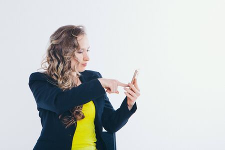 the concept of employment, interviews, digital advertising - businesswoman looking at the phone screen. Isolated on white background. Copy space. Portrait of a woman pointing to the phone with displeasureの写真素材