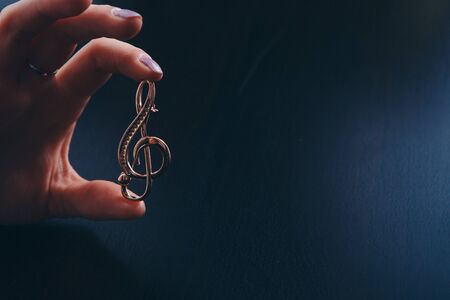 Golden violin key in the hands of women. jewellery: brooch and ringsの写真素材