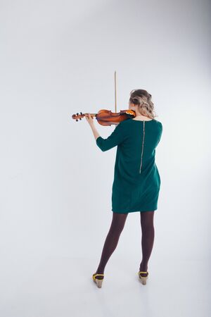 beautiful girl in green dress with small guitar in hands on white background. The concept of advertising musical instruments, fashion, symbolsの写真素材