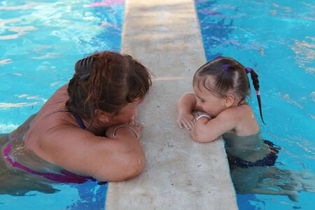 adults and children on vacation swimming in the poolの写真素材