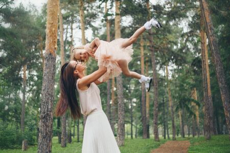 the child in the arms of the mother. Woman throws baby up. holiday, travel, family day conceptの写真素材