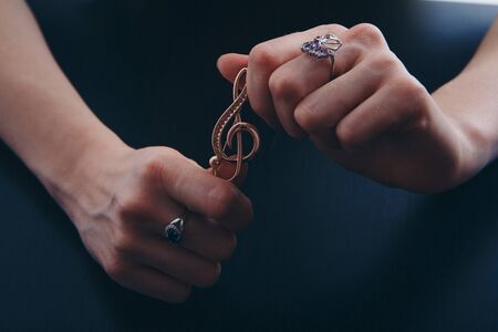 Golden violin key in the hands of women. jewellery: brooch and ringsの写真素材