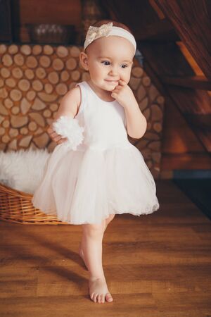 portrait of a baby biting a finger thoughtfully. a little girl in a light dress. The concept of bad habits, fashion for children, children's dayの写真素材