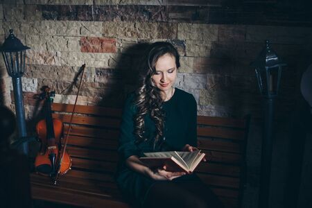 beautiful girl in a green dress reading a book. Art: the book, the violin, the lights. The concept of advertising musical instruments, fashion, symbols, artの写真素材