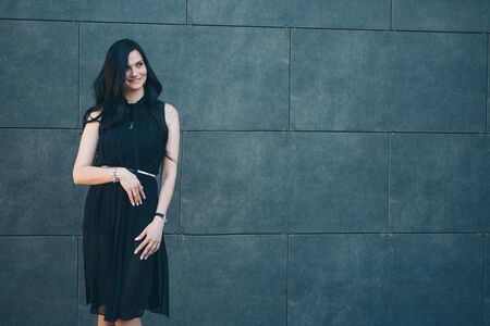 a beautiful brunette in a black dress and red shoes. Woman advertises accessories, clothes, shoesの写真素材