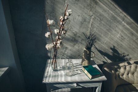 flowers in a vase on the table in a cozy room with a sofa. The concept of simple interior decoration, flowers in everyday lifeの写真素材