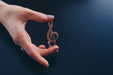 Golden violin key in the hands of women. jewellery: brooch and rings. copy spaceの写真素材