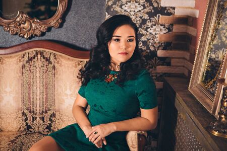 work concept, model business - fashionable stylish portrait of asian woman. model in green dress sitting on chairの写真素材