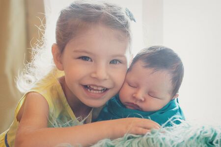 the concept of a healthy lifestyle, the protection of children, shopping - a teenager with a newborn baby playing together. Happy kids: brother and sister on white backgroundの写真素材