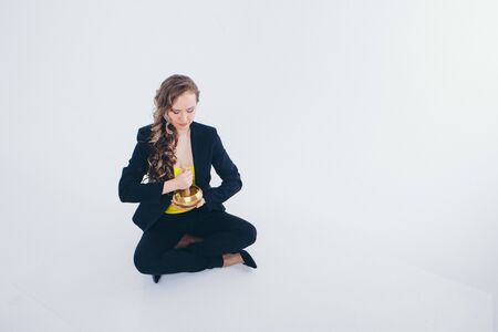businesswoman meditating. Preparation of a potion on a white background. Singing bowl with Buddhist mantra in woman's hand in a suitの写真素材