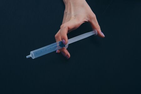 syringe on dark background. hands holding a medical device. The concept of a healthy lifestyle, health care, drug addiction, vaccination. Copy spaceの写真素材