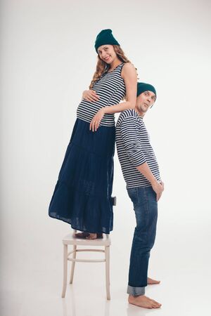 the concept of domestic violence, manifestations of emotions, sea travel. Pregnant woman mocks the guy: pulls the face. Couple in Navy suits on white backgroundの写真素材