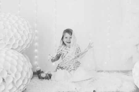A beautiful girl Teddy bear looks out from behind the curtain, a child with toy on floor. The concept of childhood, morning pastimeの写真素材