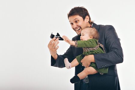 dad shows the child a black Shoe.the kid reaches for the Shoe. family tries on clothes. the concept of clothing for the whole family, advertising shoes, Cinderellaの写真素材