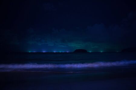 the concept of landscape design, lighting, travel: sea waves, water illumination against the night skyの写真素材