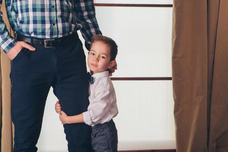 the concept of day rest, relaxation, thoughtfulness-the child rests. Son hugs leg of father. Calm expression of the man's face, relaxed postureの写真素材
