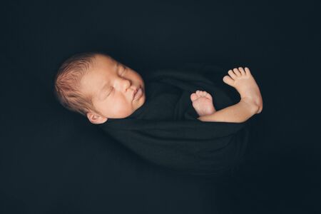 the concept of healthy lifestyle, IVF - a newborn baby sleeps under a blanket. Head, legs and armsの写真素材